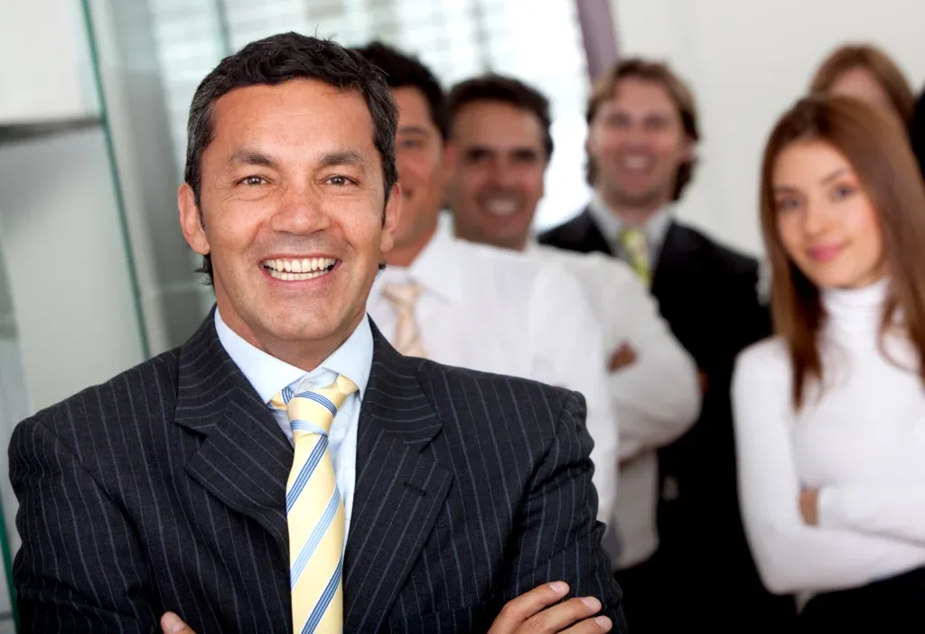 Director corporativo sonriente acompañado por equipo profesional utilizando software de Recursos Humanos para fortalecer el rendimiento empresarial.